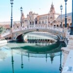 Bridge, Lampposts, Body of Water, and Buildings during Day